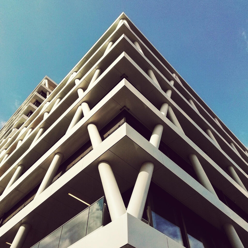 Nowoczesny budynek apartamentowy z dużymi balkonami i przeszklonymi elewacjami, widok z dołu.